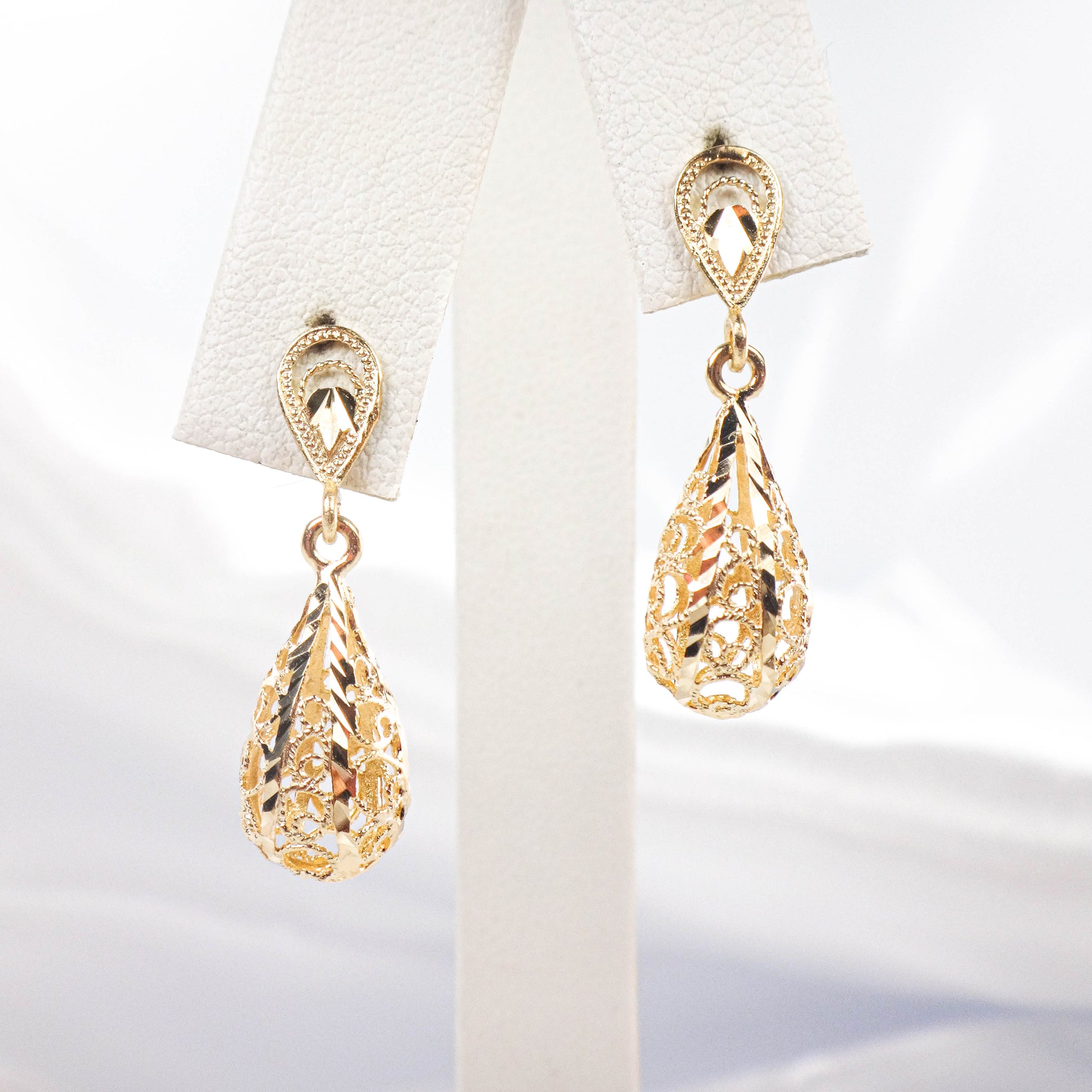 Gold teardrop earrings on a white background